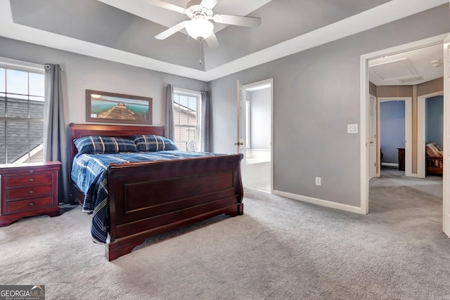 bedroom with light carpet, a tray ceiling, ceiling fan, and ensuite bathroom