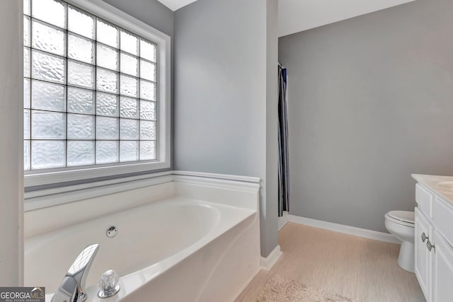 bathroom with hardwood / wood-style floors, vanity, a bath, and toilet