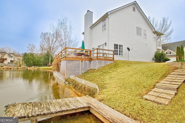 back of house featuring a lawn and a deck with water view