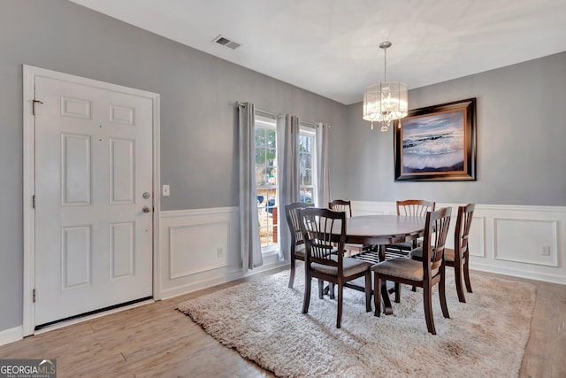 dining area with light wood-type flooring and an inviting chandelier