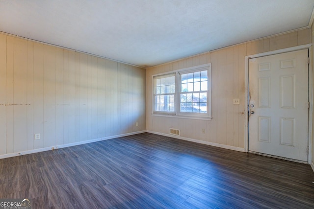 foyer entrance featuring wooden walls and dark hardwood / wood-style floors