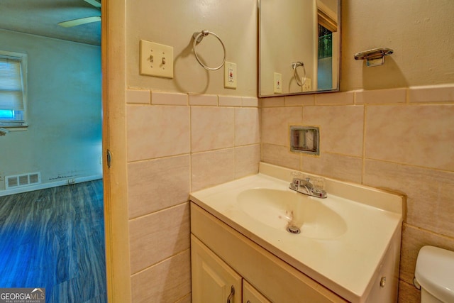 bathroom with vanity, tile walls, and toilet