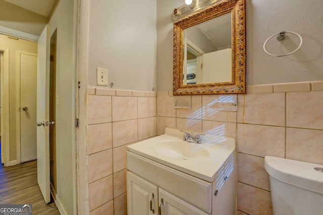 bathroom featuring vanity, toilet, and tile walls