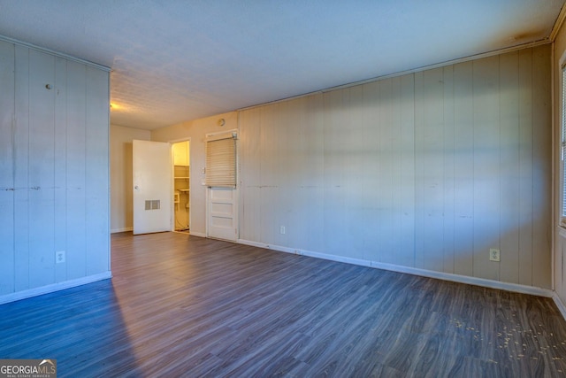 empty room with dark hardwood / wood-style floors and wood walls