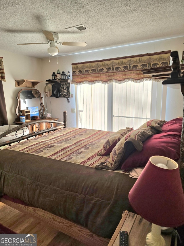 bedroom with ceiling fan and a textured ceiling