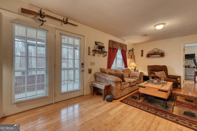 kitchen with dishwasher, sink, light hardwood / wood-style floors, and a textured ceiling