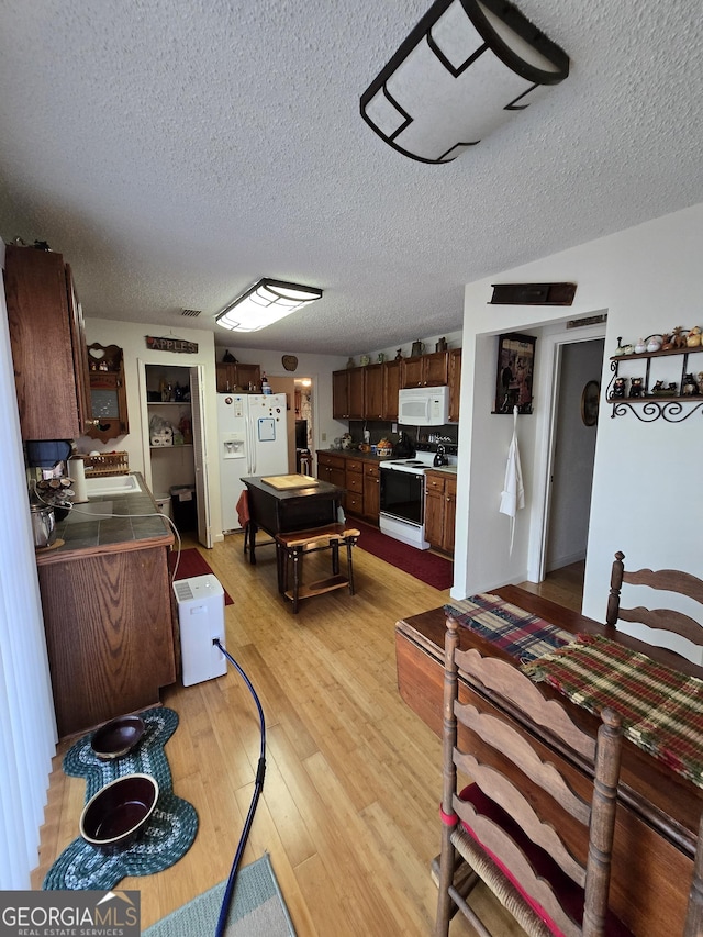 dining room with a textured ceiling, light wood-type flooring, and sink