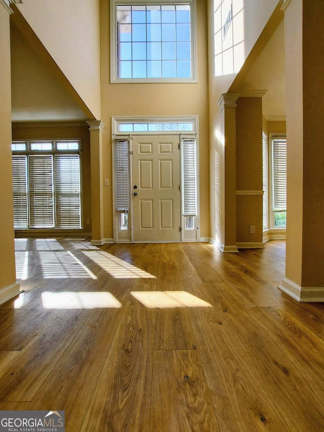 entrance foyer featuring a high ceiling, light hardwood / wood-style flooring, and ornate columns