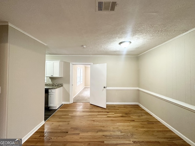 unfurnished room with wood-type flooring, a textured ceiling, and ornamental molding