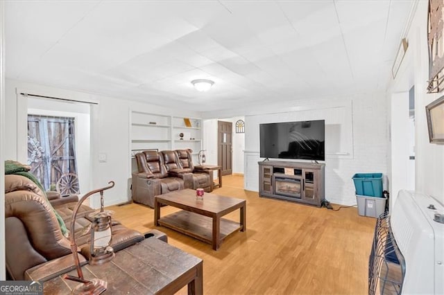 living room with built in shelves, heating unit, and light hardwood / wood-style flooring