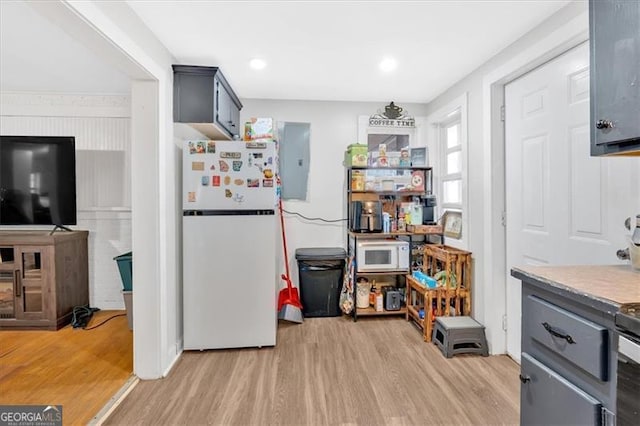 kitchen featuring gray cabinets, light hardwood / wood-style floors, white appliances, and electric panel