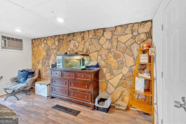 living area featuring a wall unit AC and light hardwood / wood-style floors