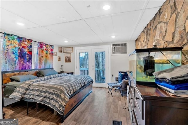 bedroom featuring hardwood / wood-style flooring, access to exterior, an AC wall unit, and french doors