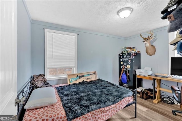 bedroom with a textured ceiling and light wood-type flooring