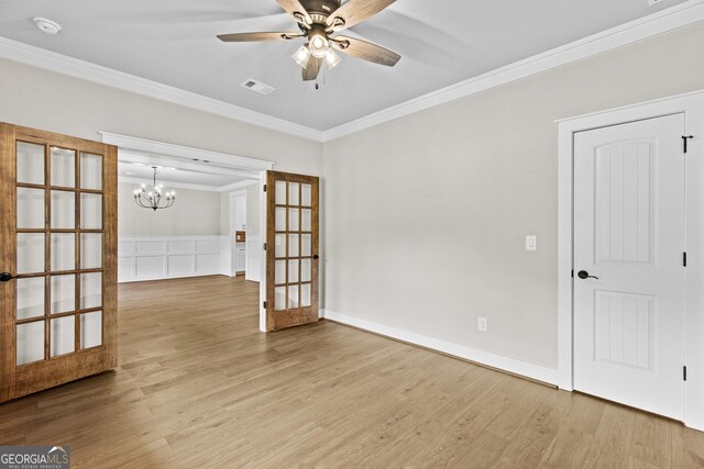 empty room featuring hardwood / wood-style floors, ceiling fan with notable chandelier, ornamental molding, and french doors