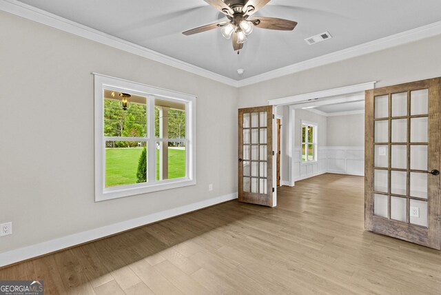 empty room with crown molding, french doors, ceiling fan, and light wood-type flooring