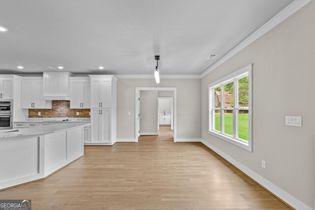 kitchen with decorative backsplash, light hardwood / wood-style flooring, white cabinets, and crown molding