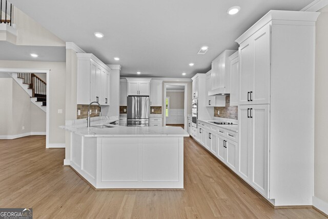 kitchen with tasteful backsplash, light hardwood / wood-style flooring, stainless steel fridge, black electric cooktop, and white cabinets