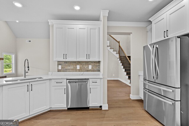 kitchen featuring decorative backsplash, light wood-type flooring, stainless steel appliances, sink, and white cabinets