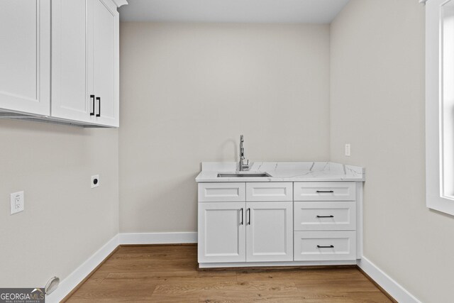 clothes washing area with light hardwood / wood-style floors, sink, cabinets, and hookup for an electric dryer