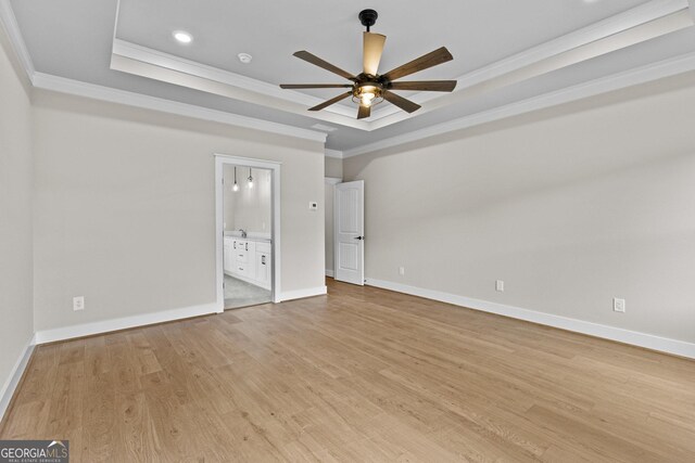 unfurnished bedroom featuring ceiling fan, a raised ceiling, crown molding, and connected bathroom