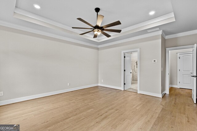 unfurnished bedroom featuring ensuite bath, ceiling fan, crown molding, light hardwood / wood-style floors, and a tray ceiling