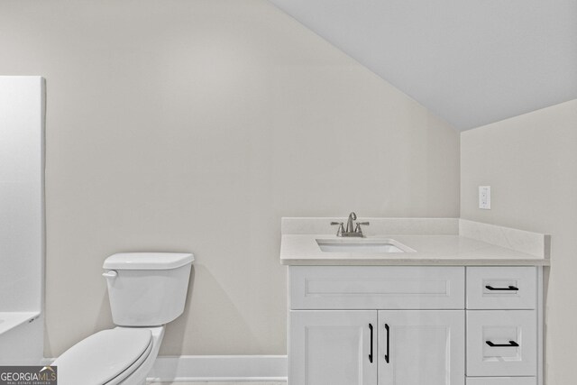 bathroom with vanity, toilet, and vaulted ceiling