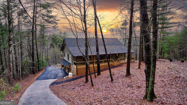 rustic home featuring a shingled roof and driveway