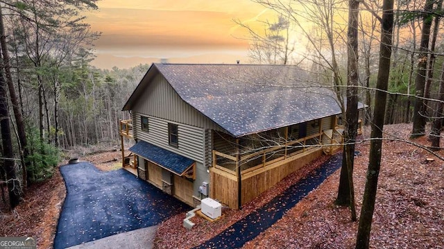 view of front of house with roof with shingles and log siding