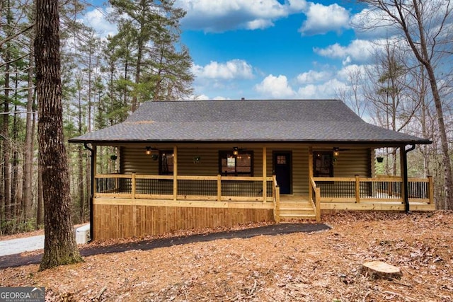 view of front of house featuring log exterior, a porch, and a shingled roof