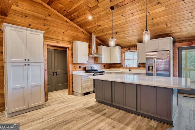 kitchen with appliances with stainless steel finishes, wall chimney range hood, a wealth of natural light, and white cabinets