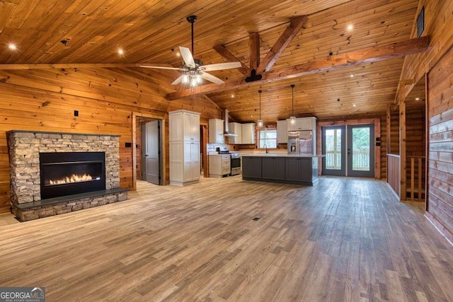 unfurnished living room with light wood-type flooring, wood ceiling, wooden walls, high vaulted ceiling, and a fireplace