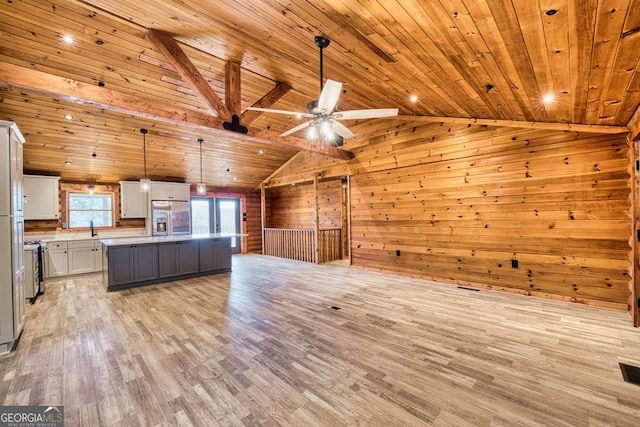 kitchen featuring light wood finished floors, wooden walls, stainless steel fridge with ice dispenser, vaulted ceiling, and a sink