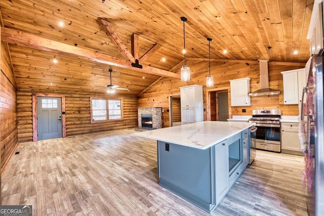 kitchen featuring wall chimney exhaust hood, stainless steel appliances, log walls, white cabinets, and hanging light fixtures