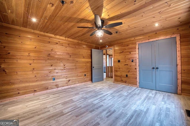 unfurnished bedroom with light hardwood / wood-style flooring, ceiling fan, wooden walls, and wood ceiling