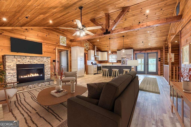 living room featuring wood walls, wooden ceiling, high vaulted ceiling, light hardwood / wood-style flooring, and ceiling fan