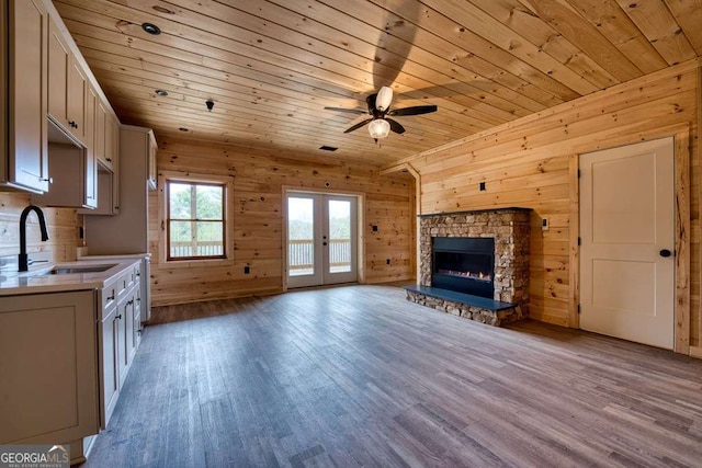 kitchen featuring wooden ceiling, wood finished floors, light countertops, a stone fireplace, and a sink