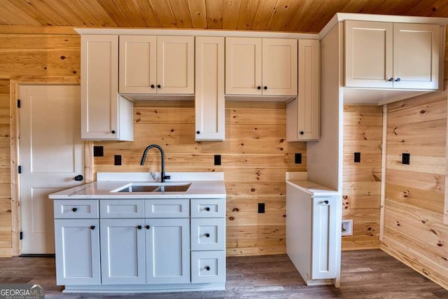 kitchen with dark wood finished floors, light countertops, a sink, wooden walls, and wooden ceiling