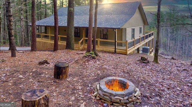 back house at dusk featuring an outdoor fire pit and cooling unit