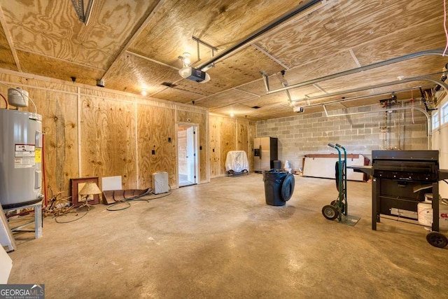 garage featuring a garage door opener, concrete block wall, and electric water heater