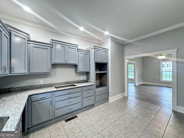 kitchen with ceiling fan, light stone counters, light hardwood / wood-style flooring, crown molding, and gray cabinets