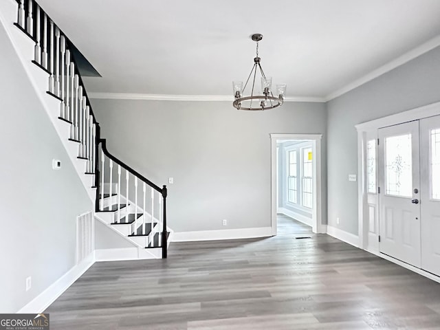 entrance foyer with dark hardwood / wood-style floors, ornamental molding, and a chandelier