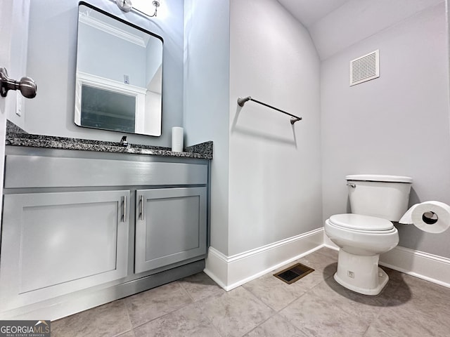 bathroom with tile patterned flooring, vanity, toilet, and vaulted ceiling