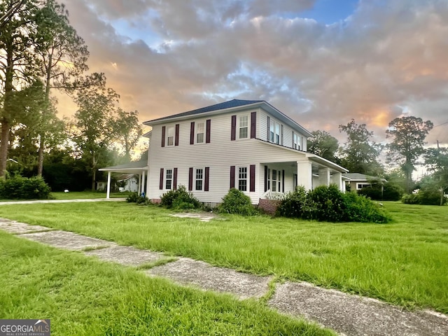 property exterior at dusk featuring a lawn and a carport