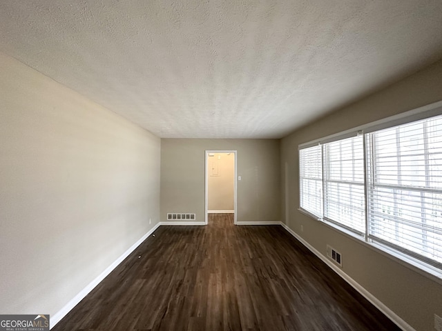 unfurnished room with a textured ceiling and dark wood-type flooring