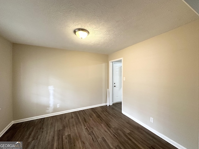 spare room featuring dark wood-type flooring and a textured ceiling