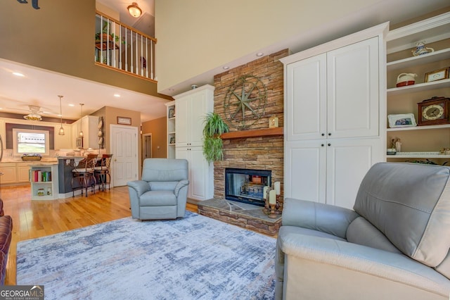 living room featuring a fireplace, a high ceiling, and light hardwood / wood-style floors