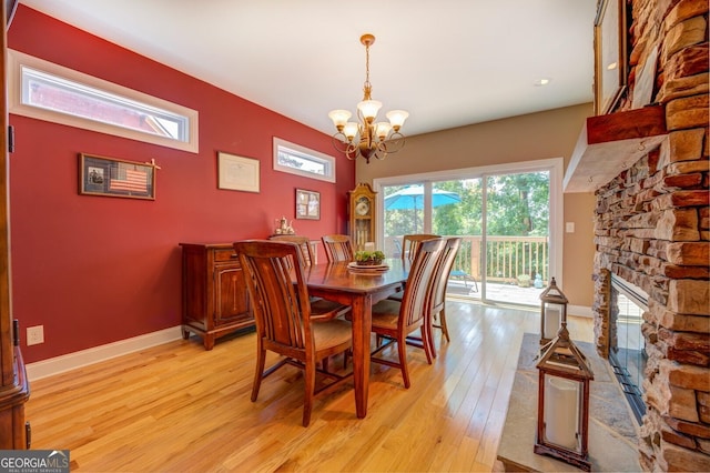 dining room with a fireplace, light hardwood / wood-style floors, and a notable chandelier