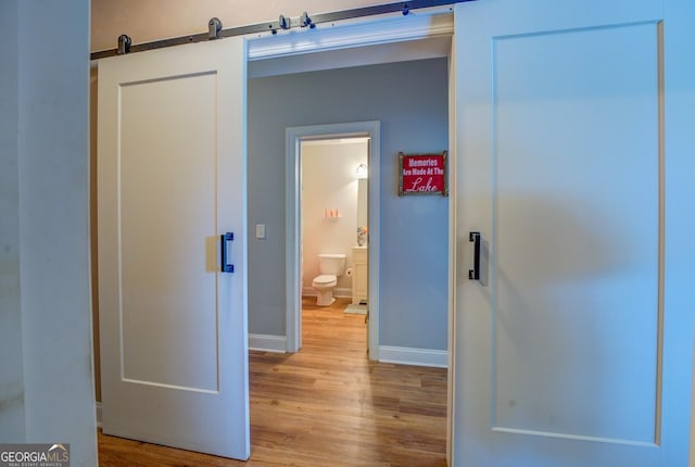 corridor featuring a barn door and light hardwood / wood-style floors