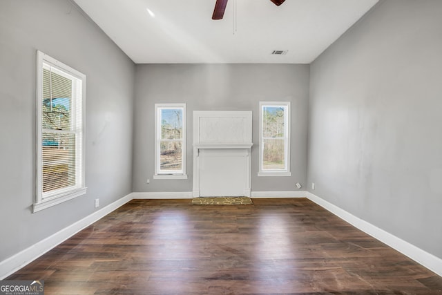 spare room featuring ceiling fan, dark wood-type flooring, and a healthy amount of sunlight